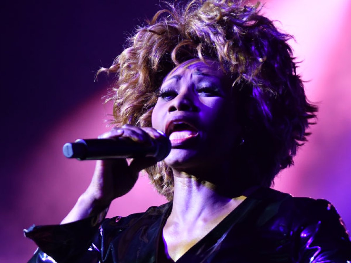 a person standing on a stage with purple hair looking at the camera