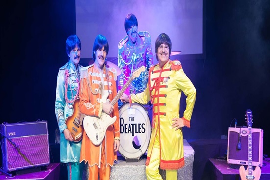 01_laerdalferiepark_beatles_c_dietmar_bramsel-1 a group of people standing on a stage posing for the camera