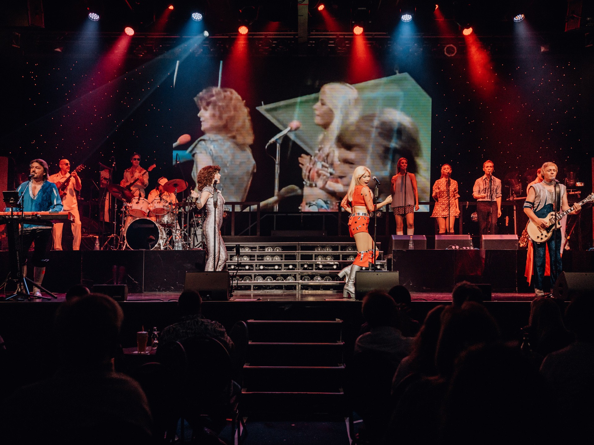 Musicians performing on stage with large screen backdrop showing close-ups.